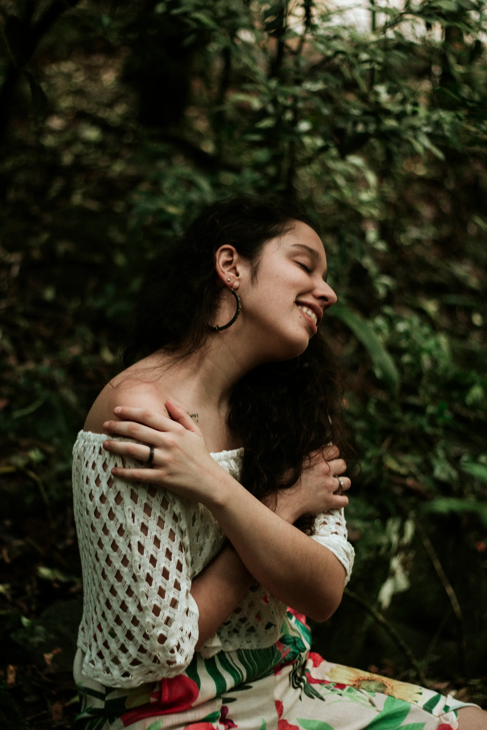 Dra. Andressa Paz se abraçando em meio à natureza — abraço é medicina